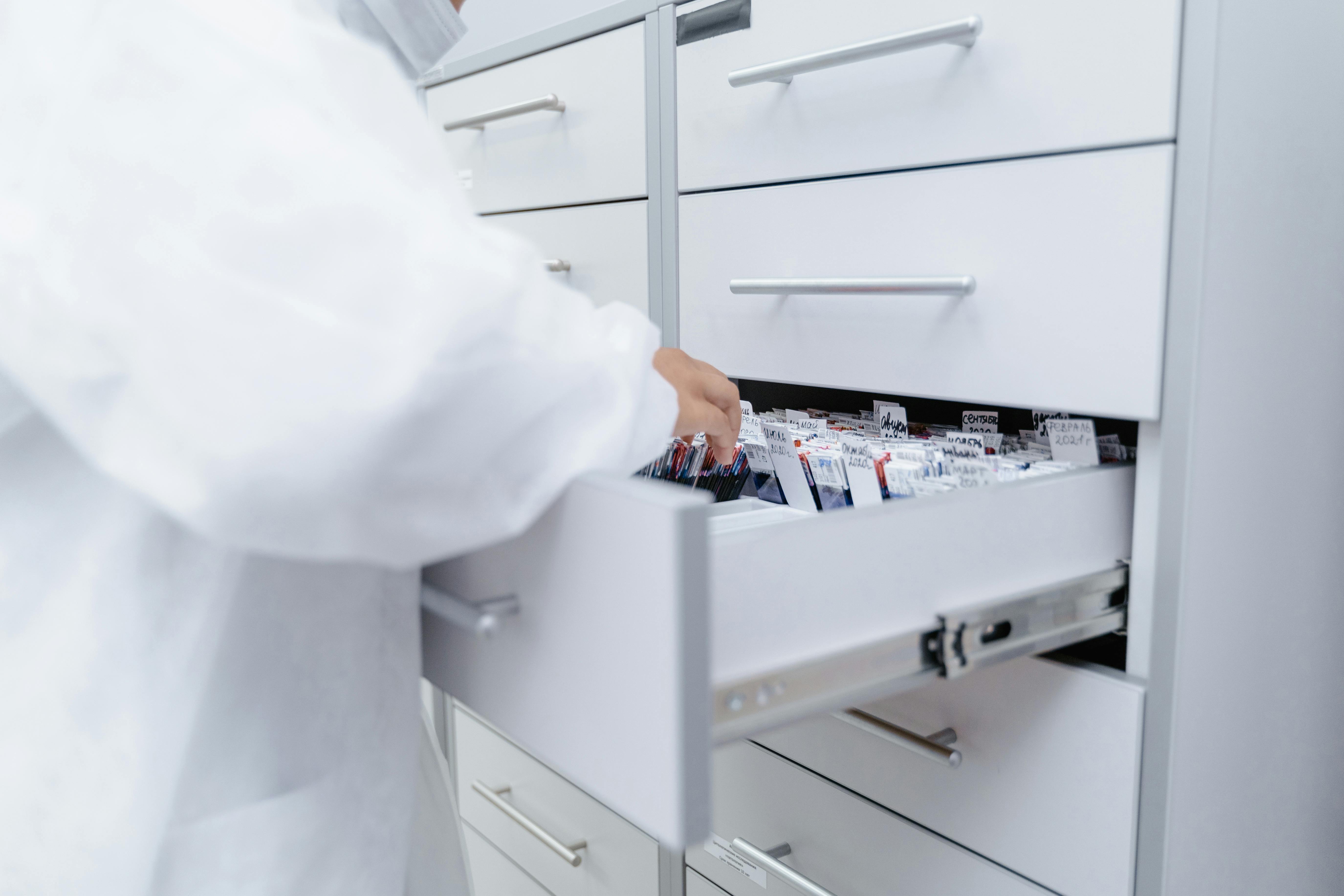 person in lab coat looking through records