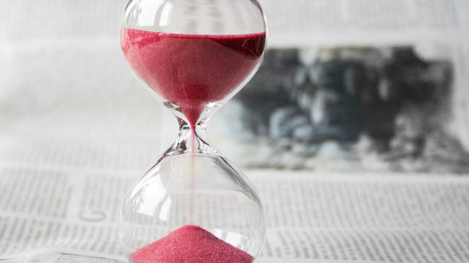 Hourglass with red sand on top of newspaper