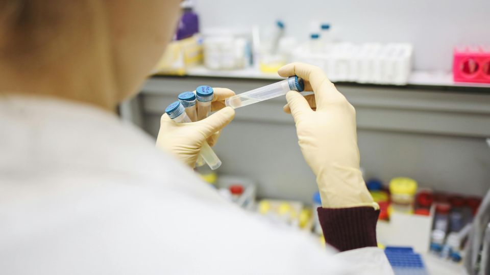 person in lab coat holding sample tubes