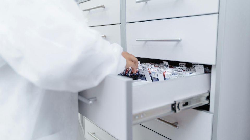 person in lab coat looking through records