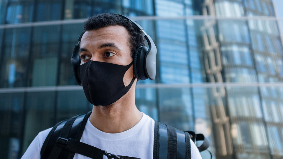 Image of young man wearing headphones and a mask