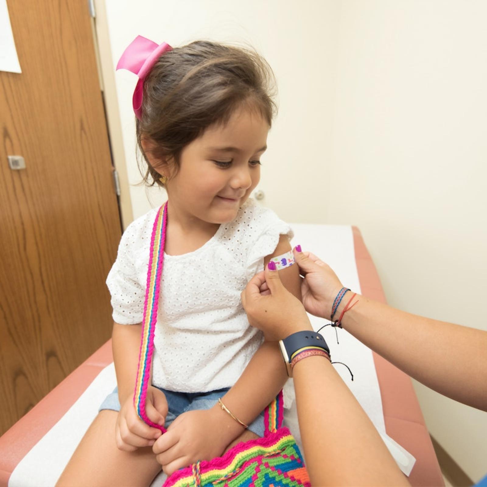 Little girl receiving bandaid on arm