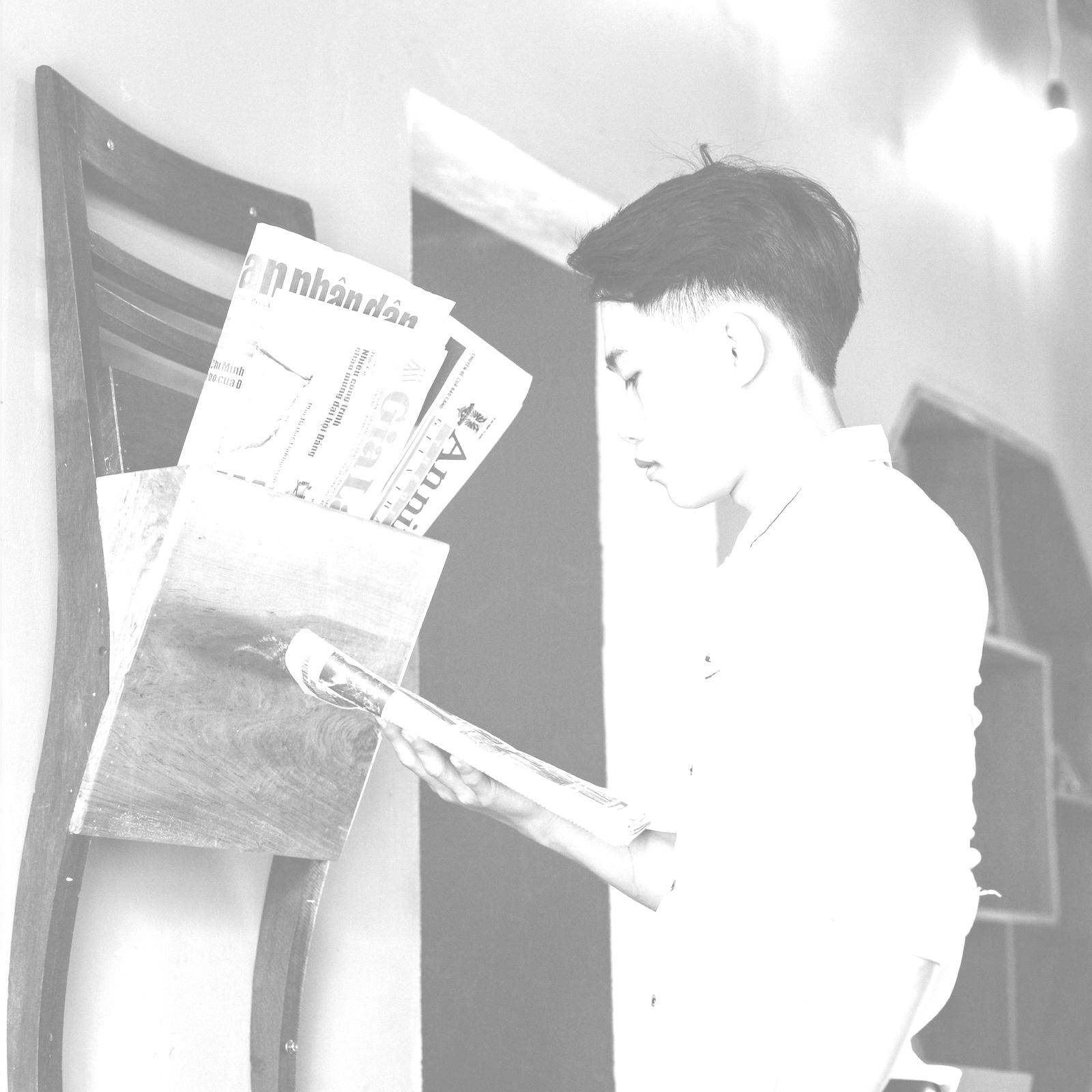 Young man reading newspaper.